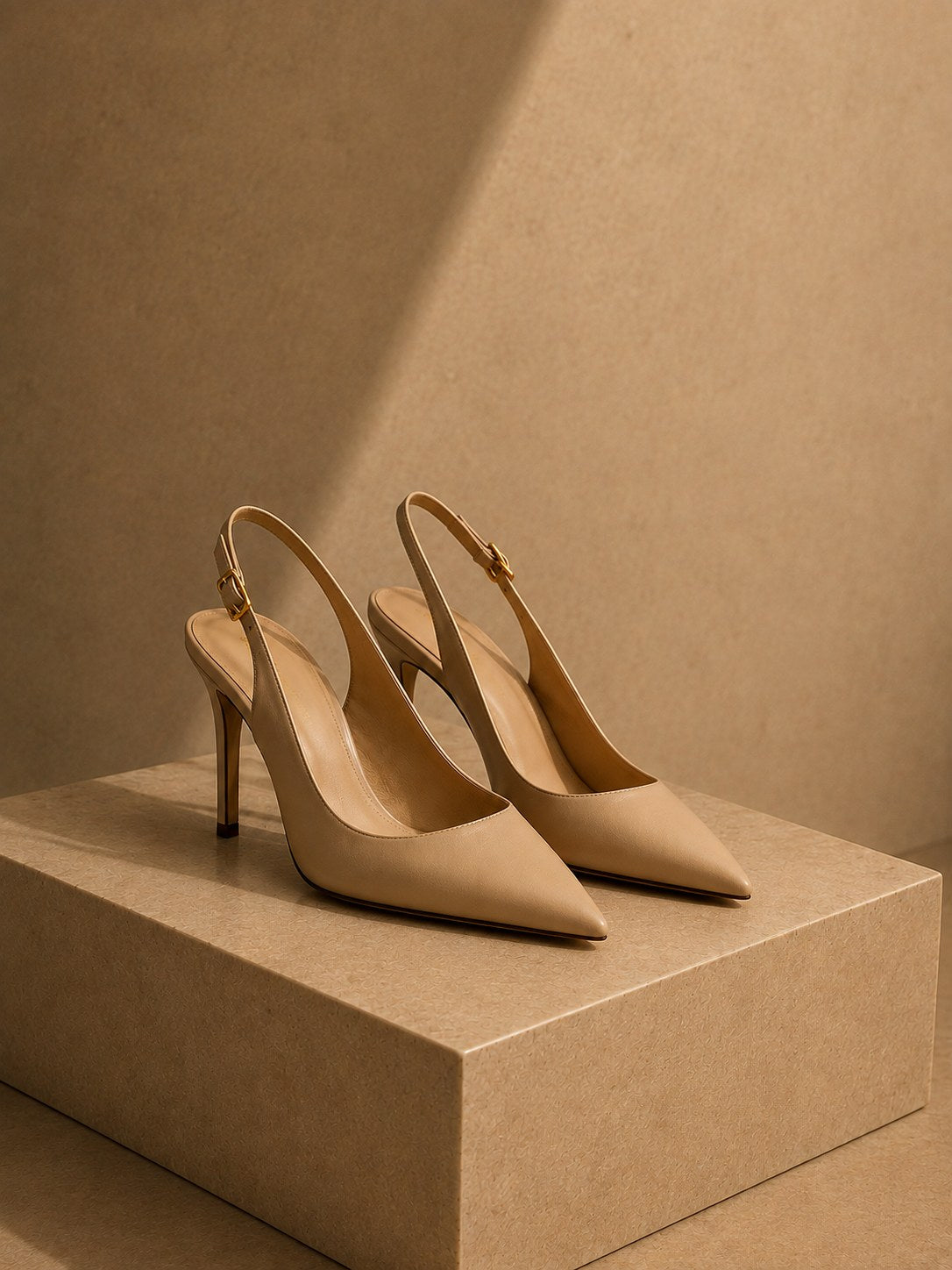 Symbolbild, KI-generiert: Beige Slingback-Pumps mit spitzer Kappe auf einem Steinpodest
